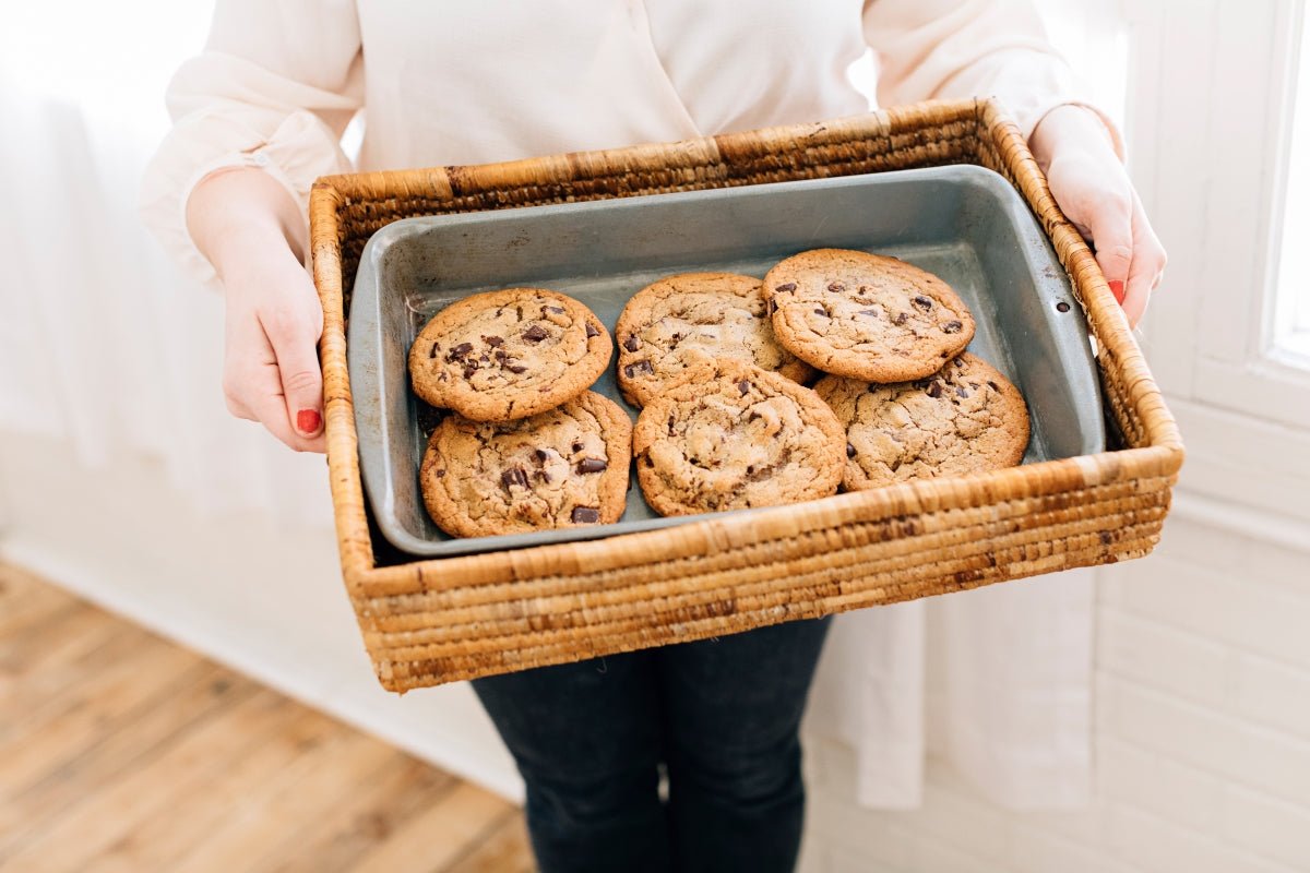 Banana Leaf Nesting Tray Set filled with freshly baked chocolate chip cookies in a woven tray held by a person.